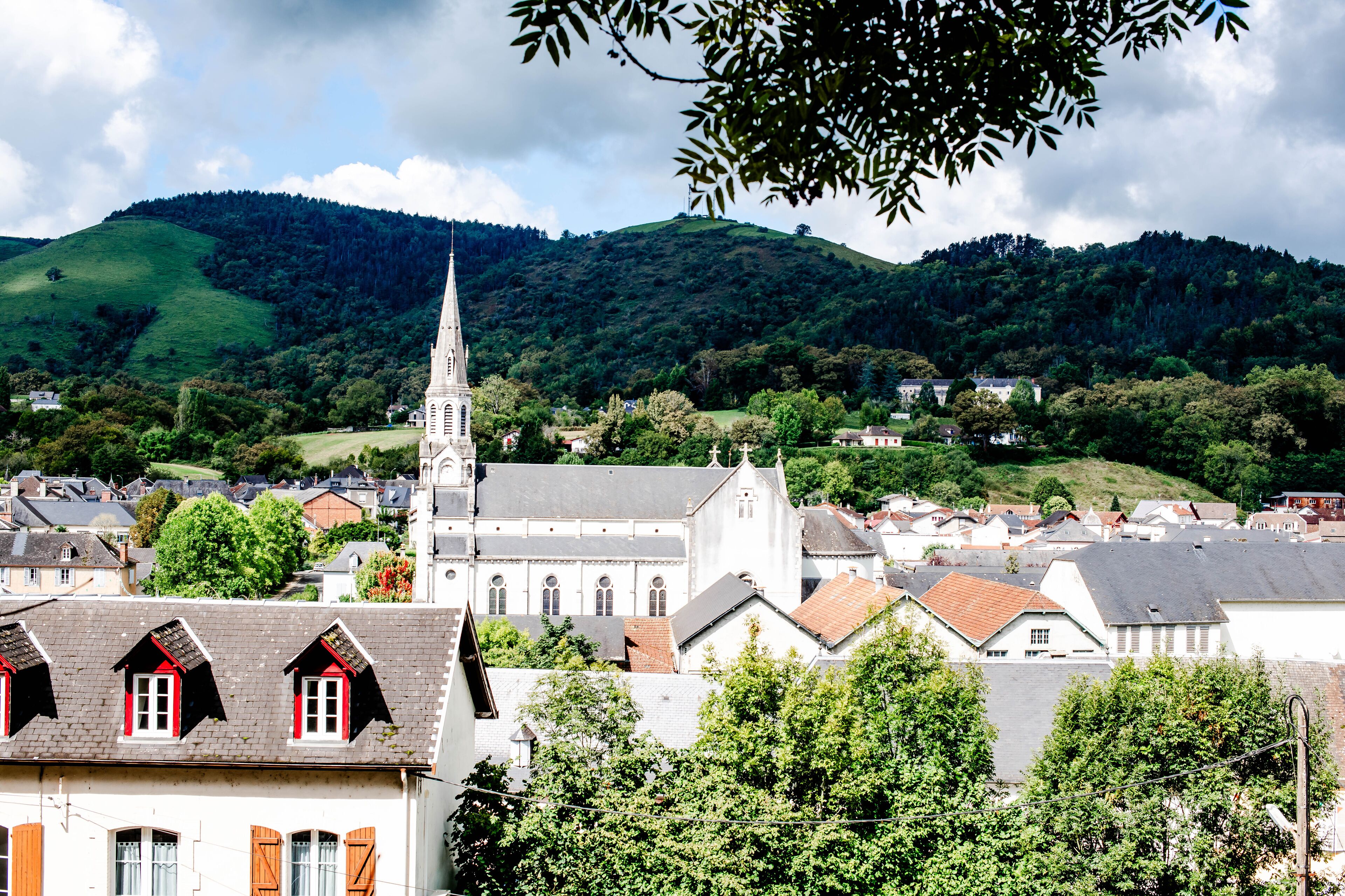 A town with a prominent church, surrounded by lush green hills and residential buildings.