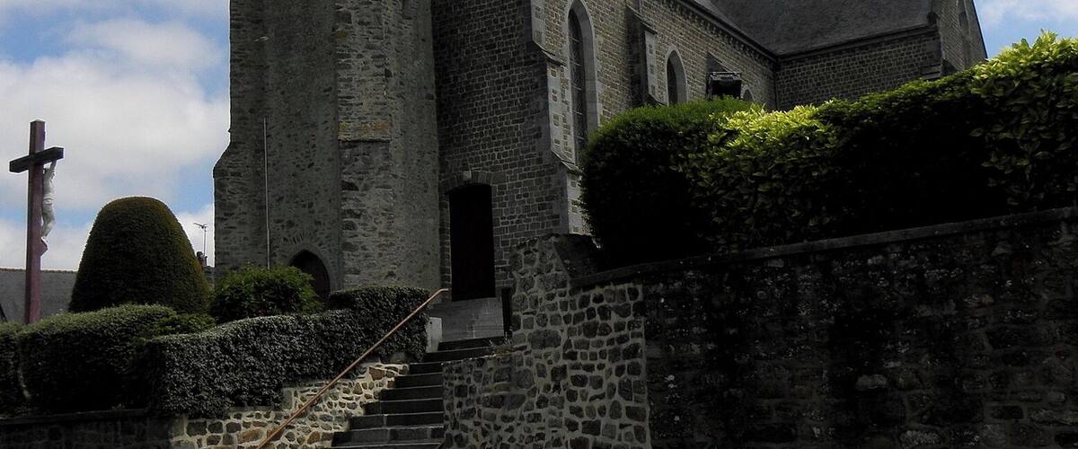 A stone church with a tall steeple and a cross at the top.
