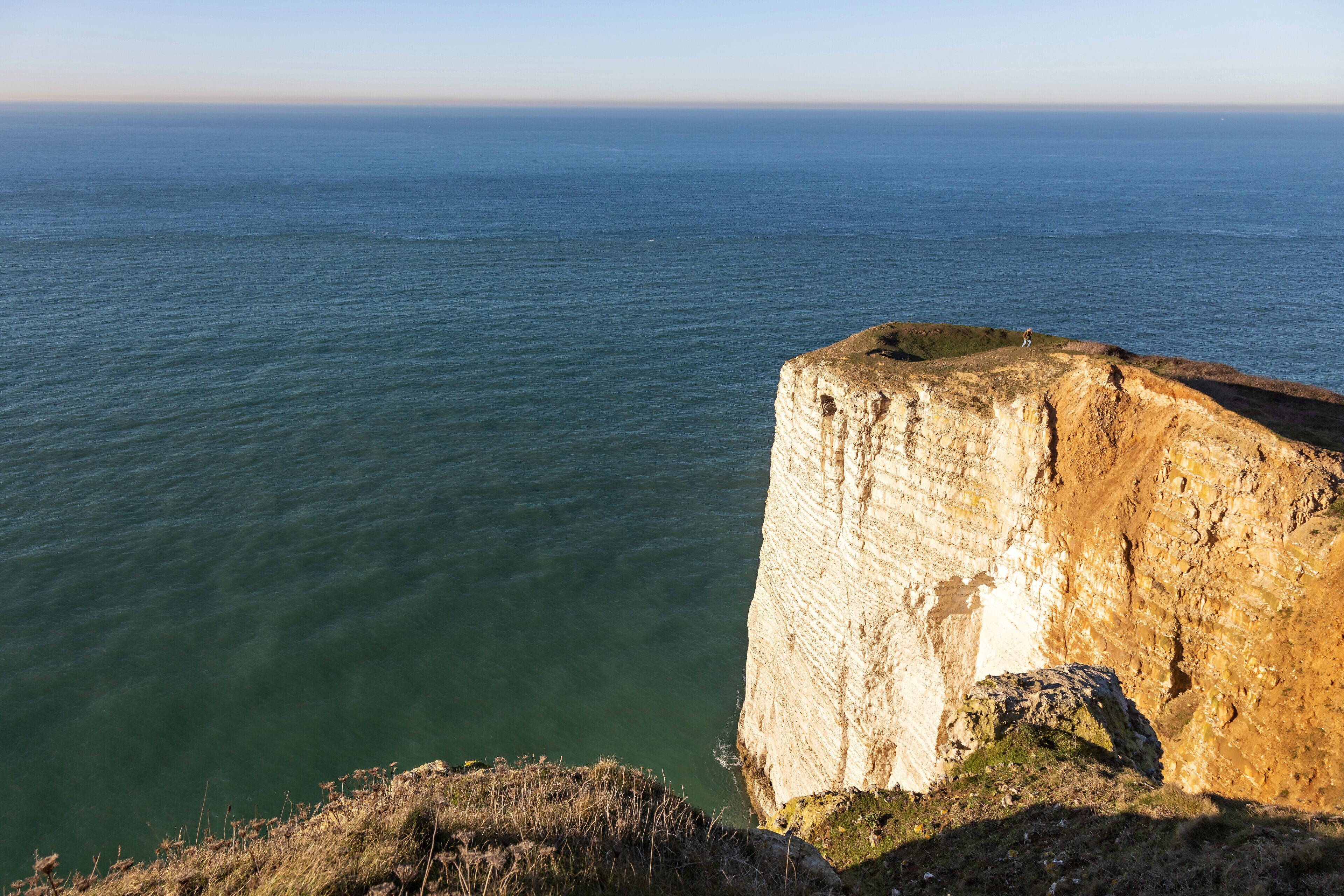 A coastal cliff with a clear view of the ocean.
