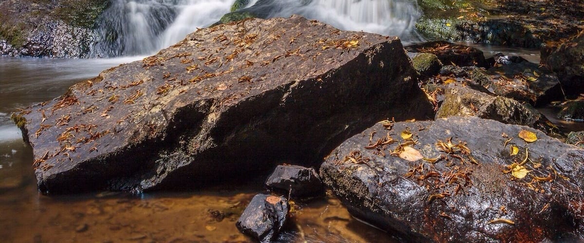 A waterfall cascading over rocks in a forested area.