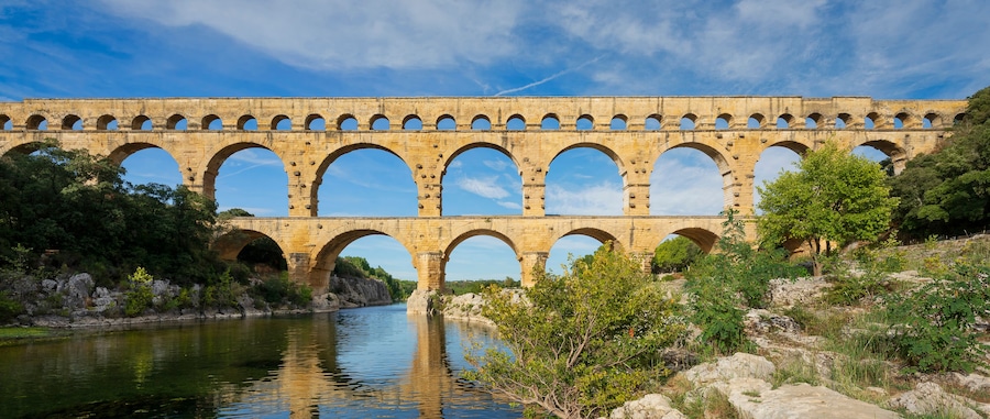 Un acquedotto in pietra con numerose arcate che superano un fiume.