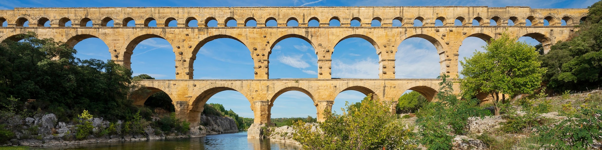 Un aqueduc en pierre, doté de plusieurs arches, enjambe une rivière.