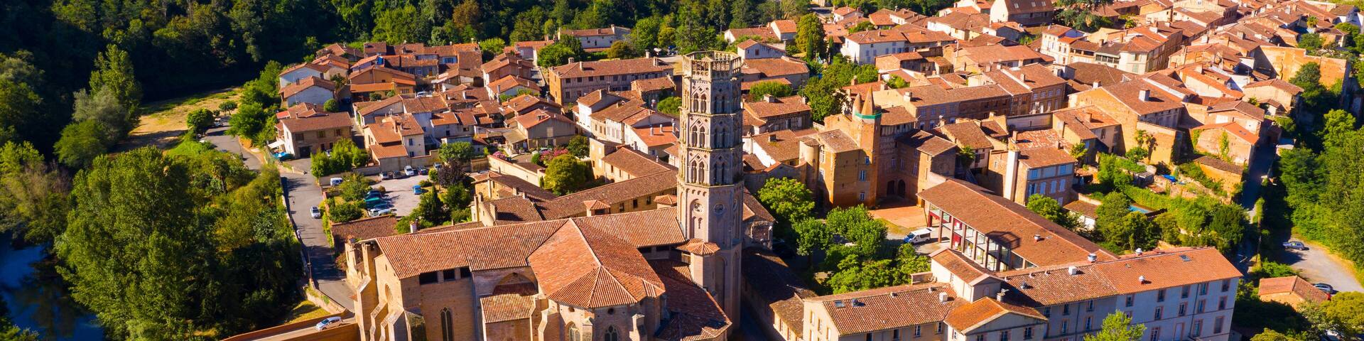 Scenic aerial view of French commune of Rieux-Volvestre on bank of Arize river at sunny summer day