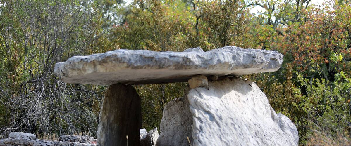 A large stone structure balanced on rocks in a natural setting.