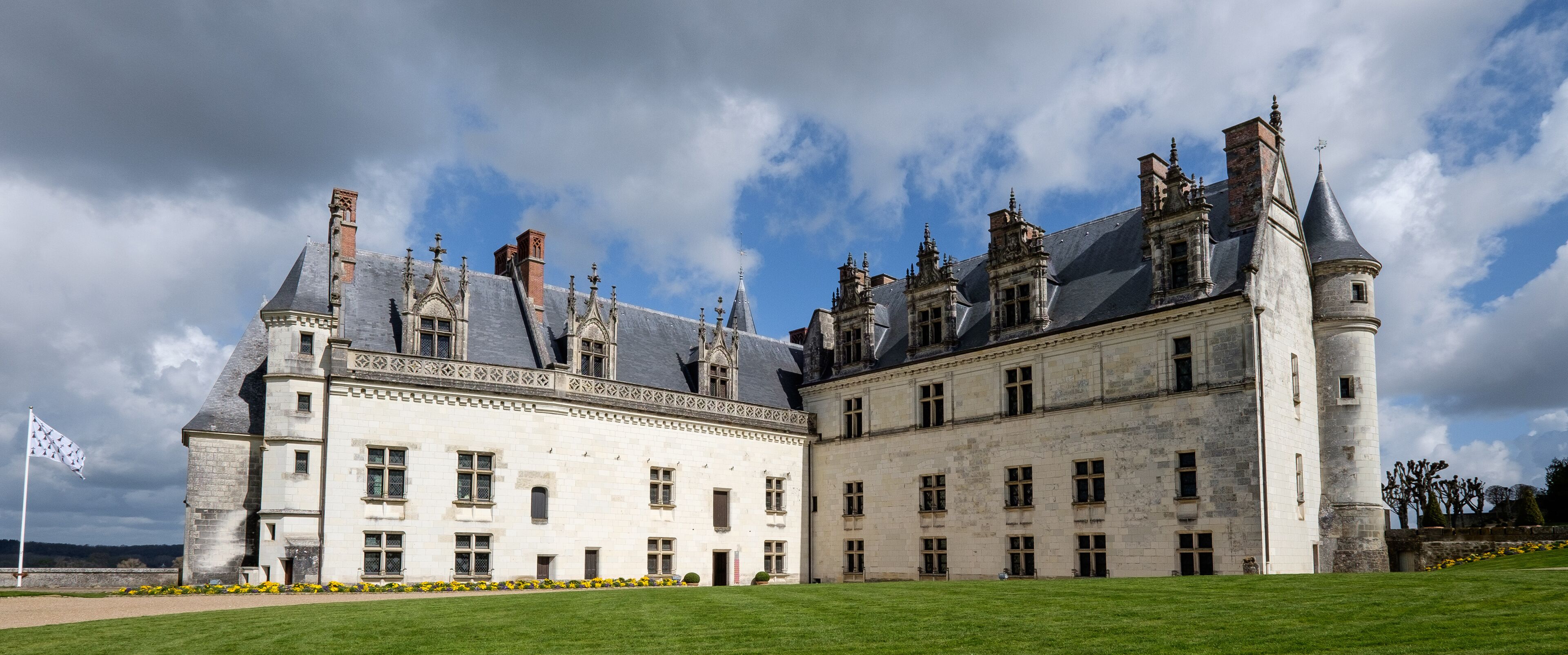 A historic castle with a large courtyard, tall towers, and a flag.