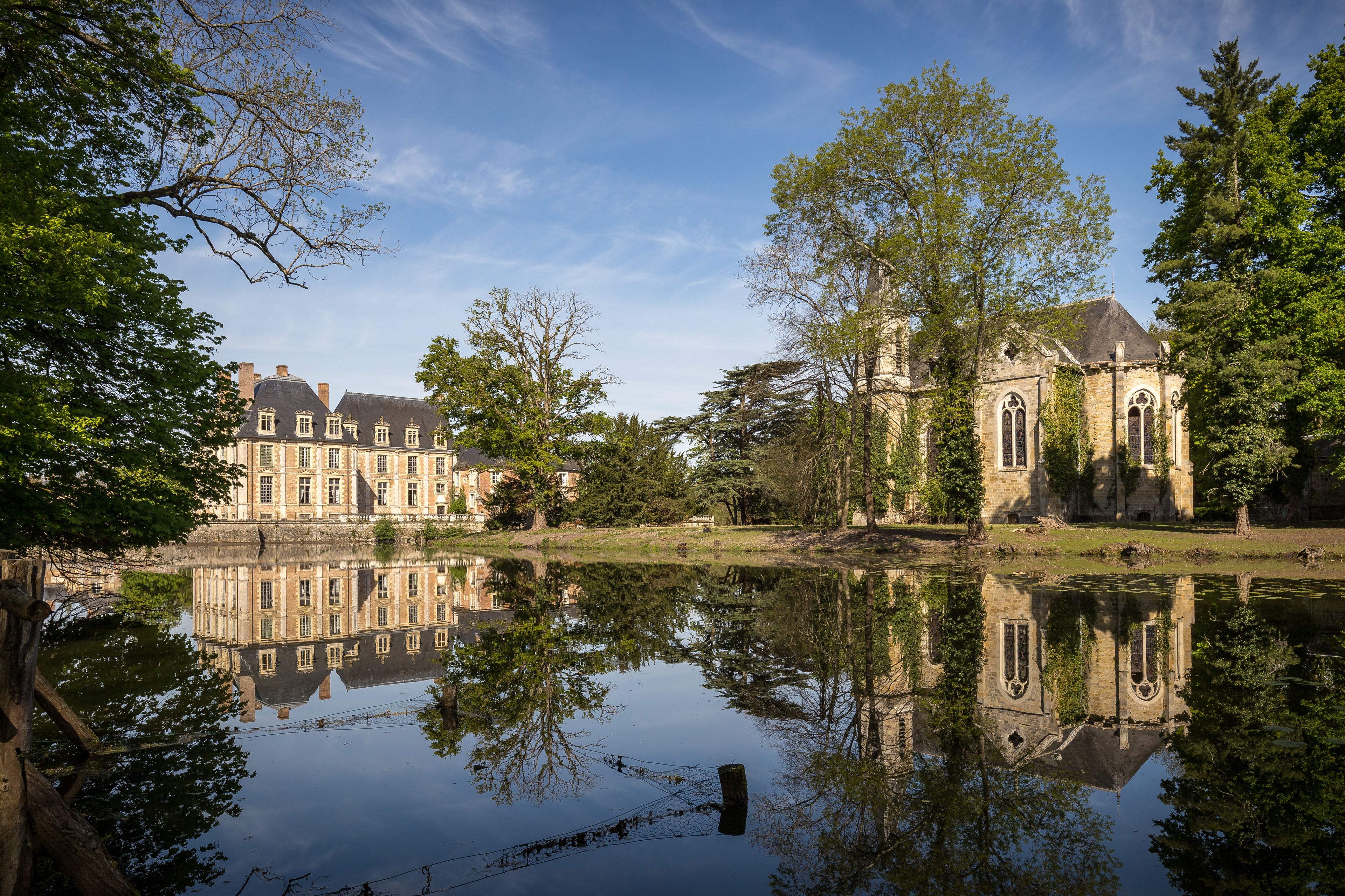 A historic building with a large pond reflecting its architecture.