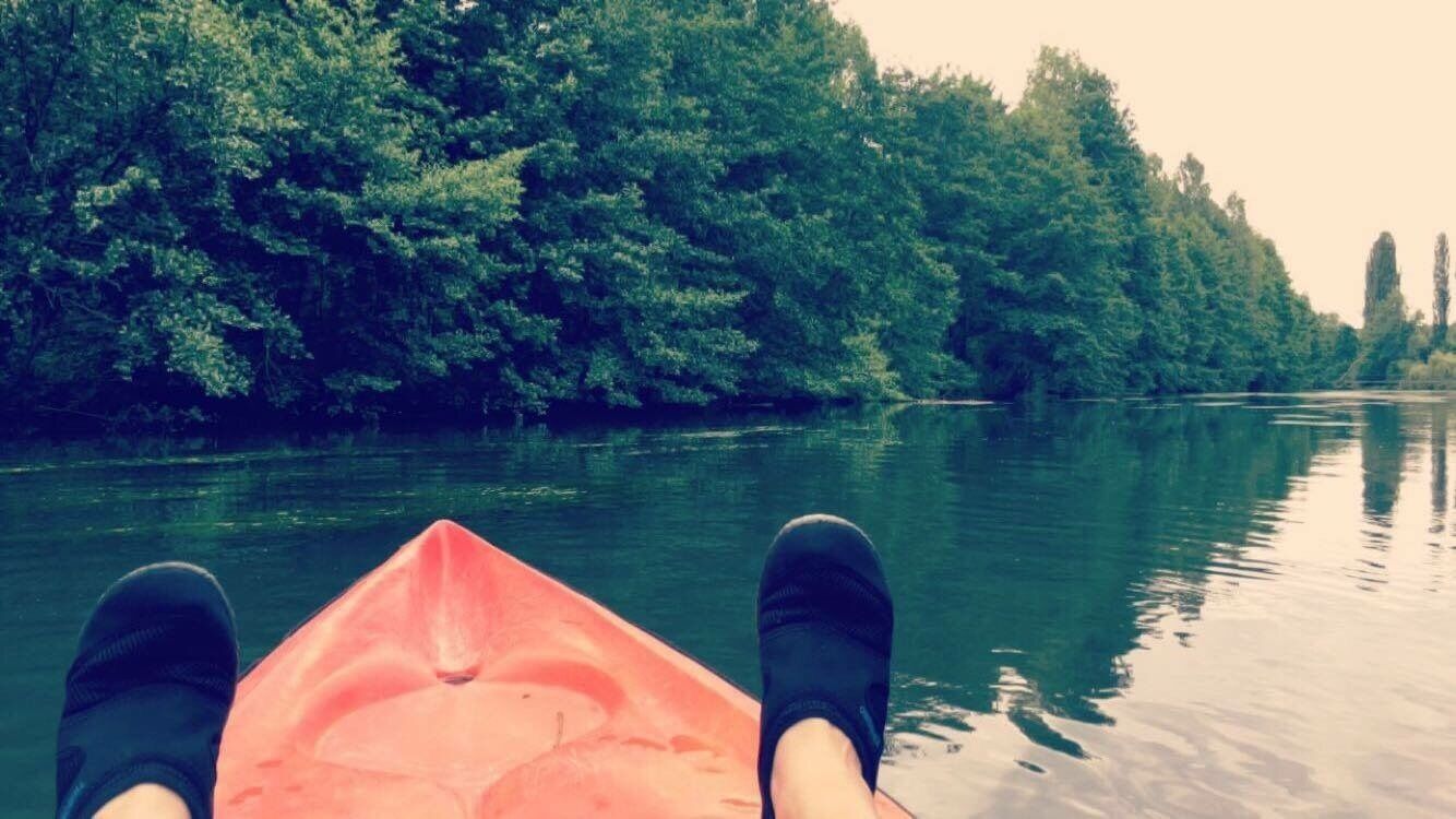 A kayak on a calm river surrounded by dense green trees.