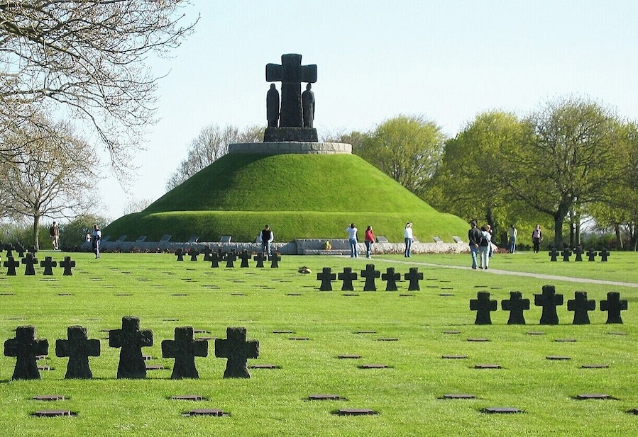 Un cementerio con numerosas cruces y un monumento de piedra destacado.