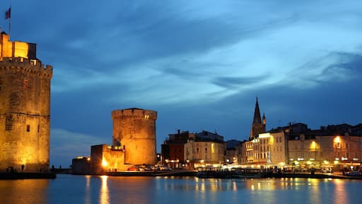 Eine historische Stadtansicht mit beleuchteten Türmen und Gebäuden am Wasser.