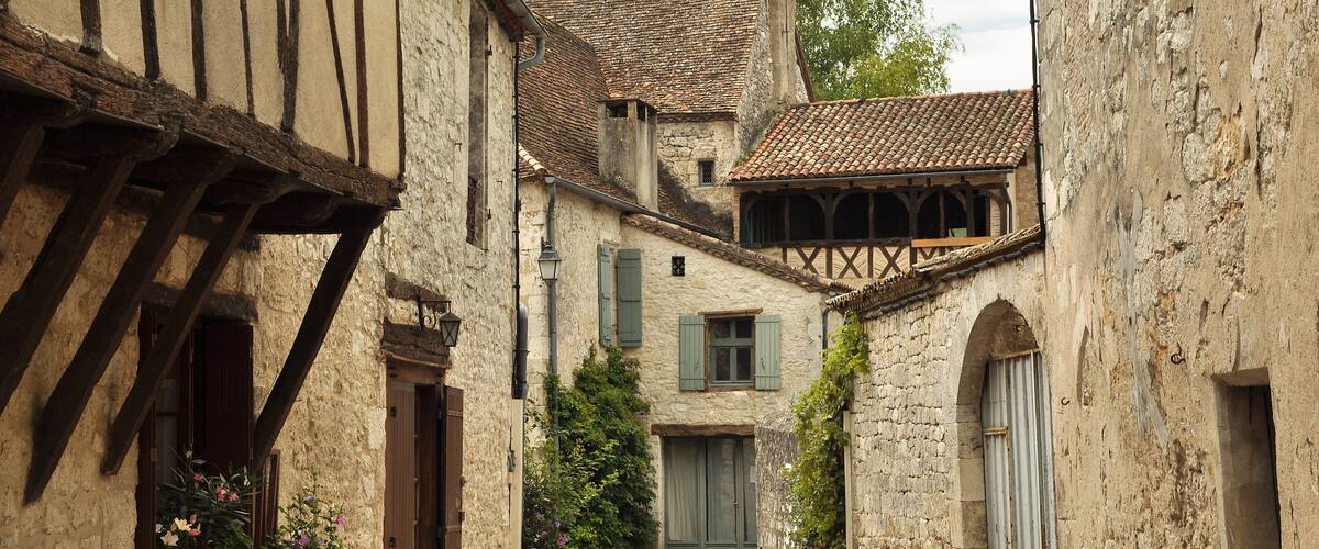 A narrow cobblestone street flanked by historic buildings with timber framing and stone walls.