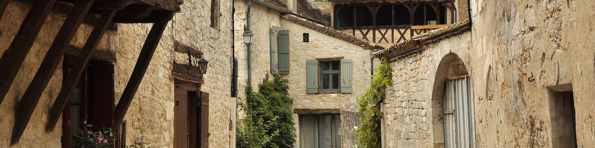 A narrow cobblestone street flanked by historic buildings with timber framing and stone walls.