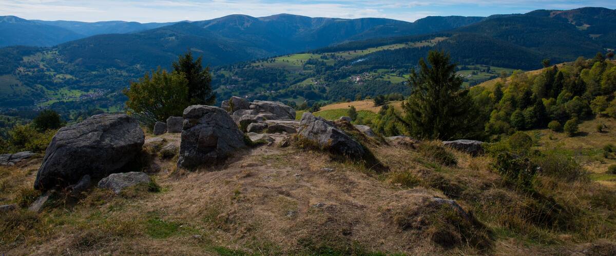 A mountainous landscape with large boulders, dense forests, and rolling hills.