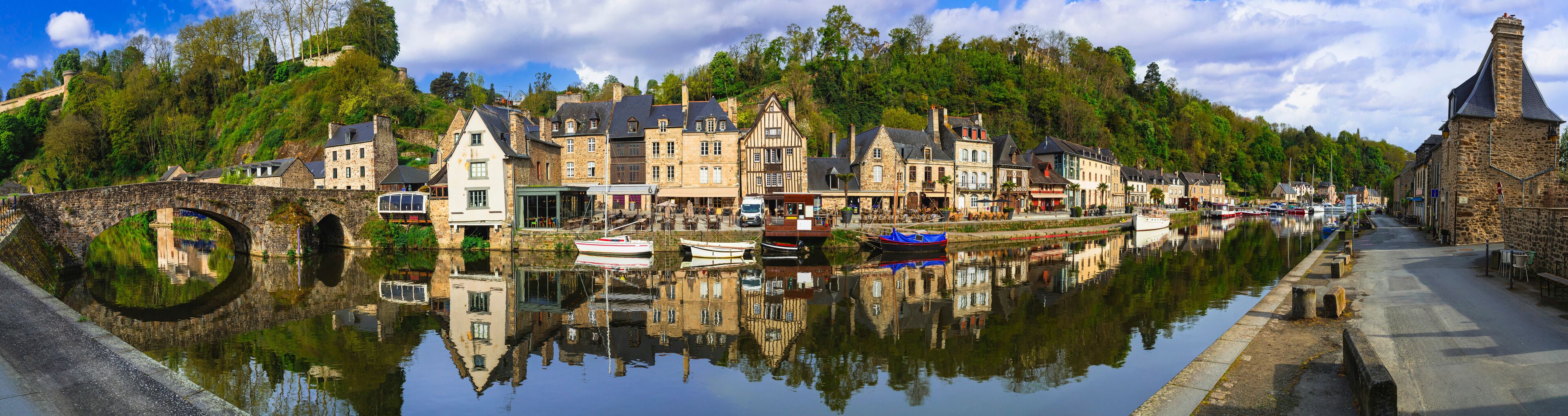 A historic town with stone buildings, a canal, and boats.
