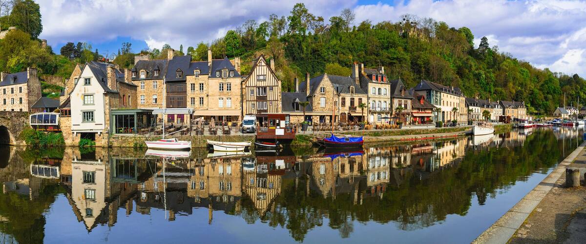 A historic town with stone buildings, a canal, and boats.