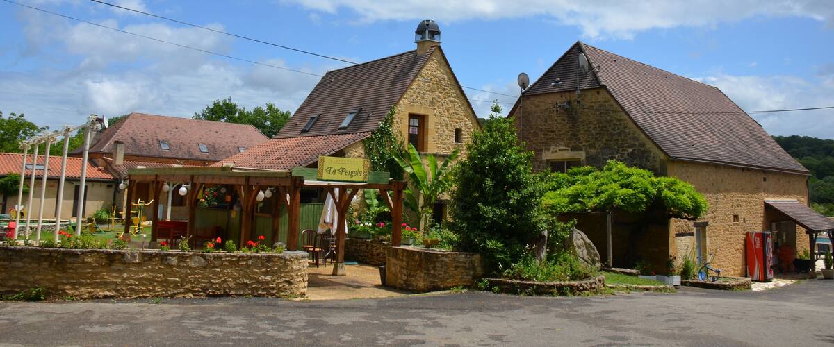 A stone building with a sign reading "La Pergola" and a covered outdoor seating area.