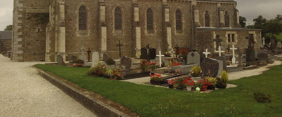 A church with a tall steeple and a cemetery in front.