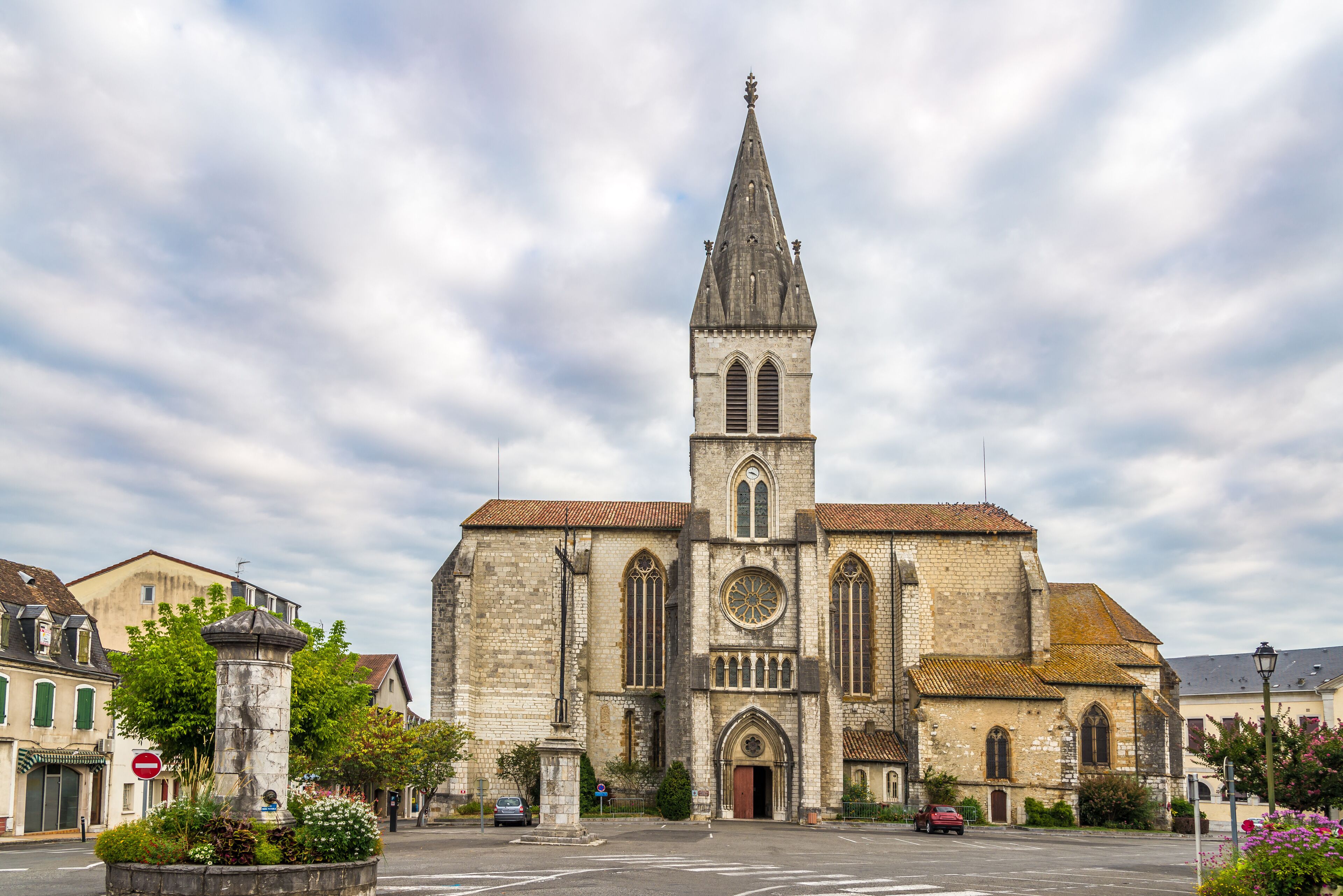 A historic church with a tall spire, a large rose window, and a stone facade.