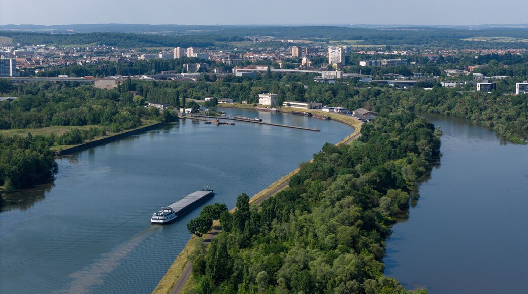 vue aérienne au dessus de la Moselle, une péniche avance sur l'eau. AU fond on aperçoit la ville de Thionville