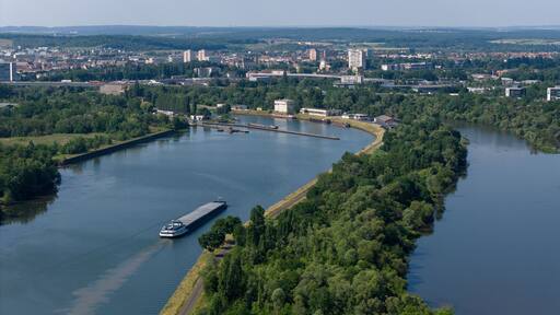 vue aérienne au dessus de la Moselle, une péniche avance sur l'eau. AU fond on aperçoit la ville de Thionville