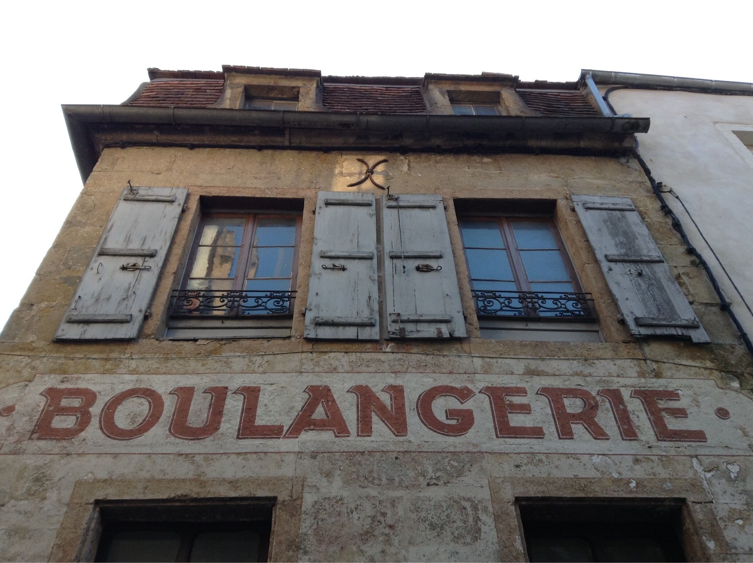A building with the sign "BOULANGERIE" and shuttered windows.