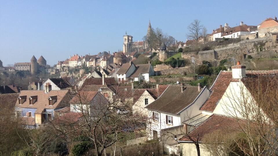 A town with historic buildings, a prominent church tower, and a castle on a hill.