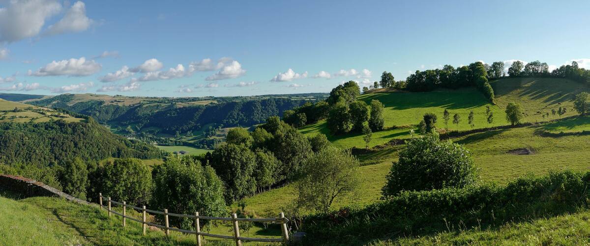 Rolling hills, a stone wall, and a wooden fence in a lush green valley.