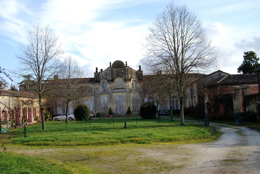 A historic building with a large central dome, surrounded by a grassy courtyard and leafless trees.