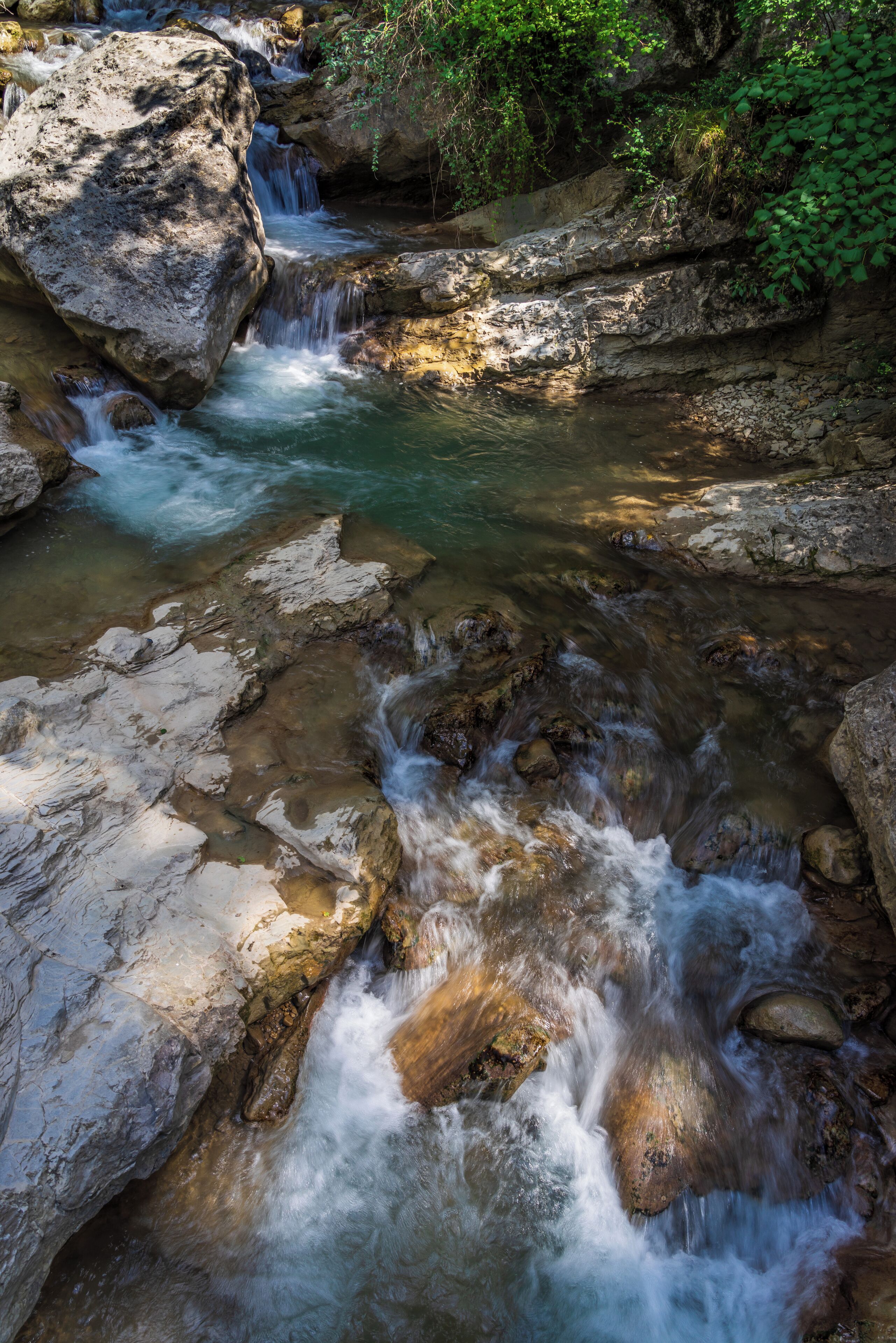 A flowing river with rocks and a waterfall.