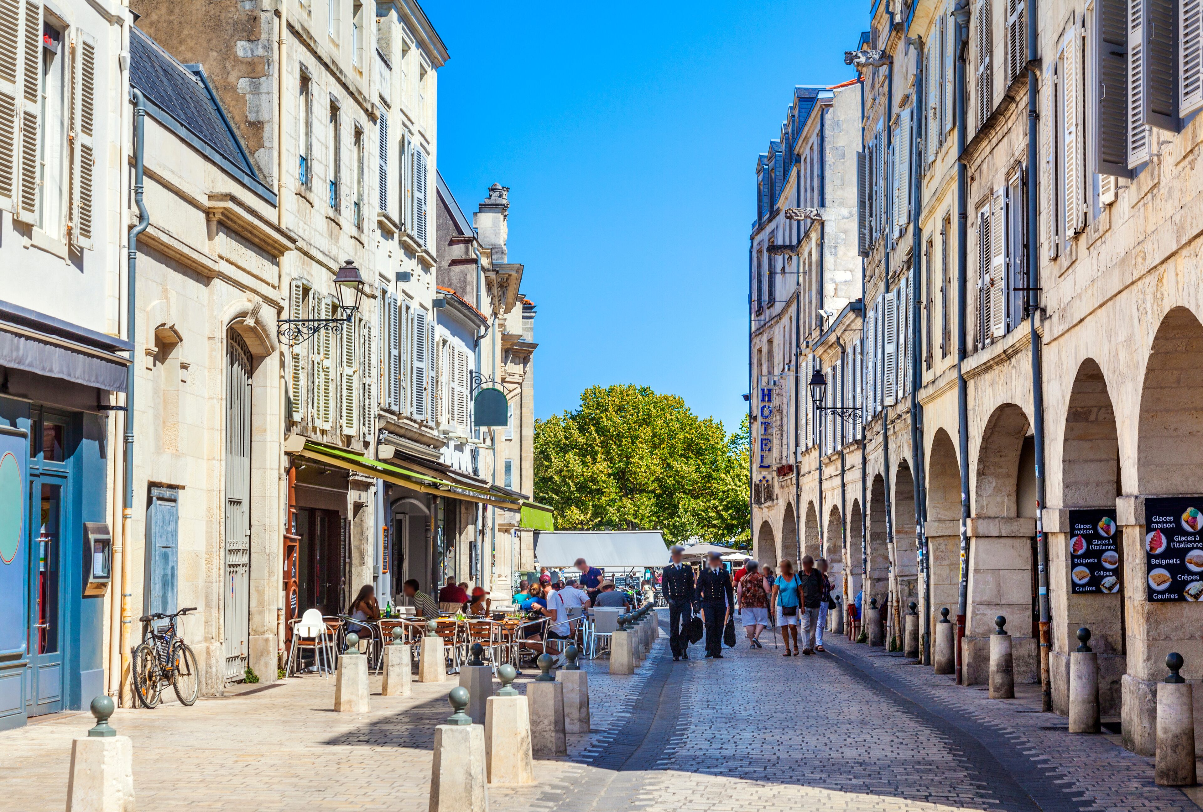 A cobblestone street lined with historic buildings, outdoor cafes, and pedestrians.