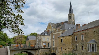 Un pont de pierre enjambant une rivière, des bâtiments historiques et le clocher d’une église.