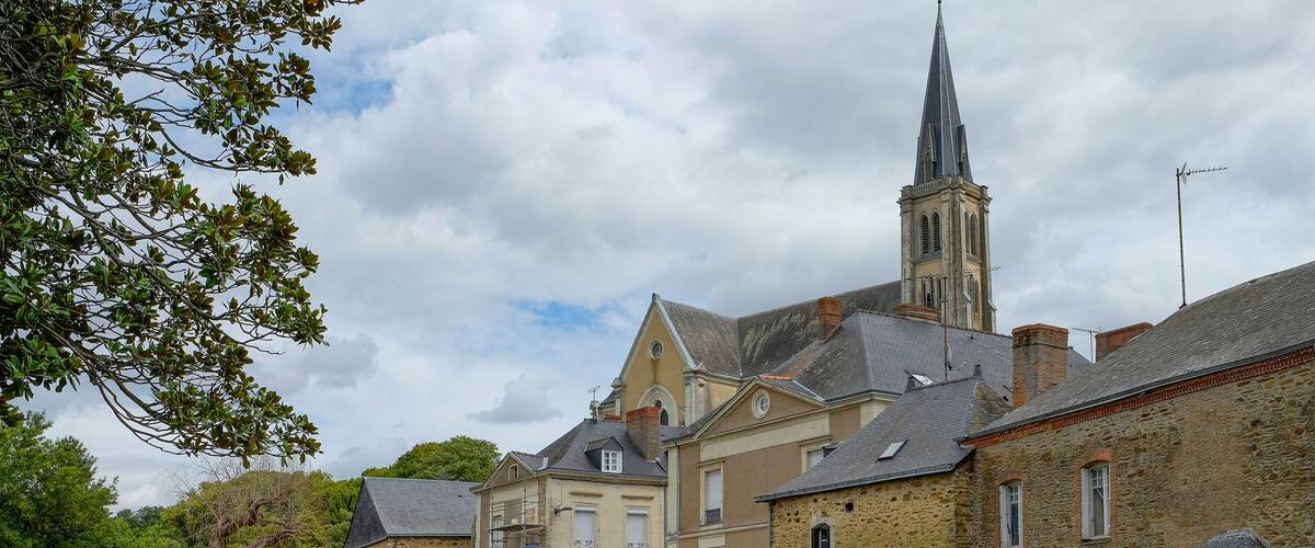 A stone bridge over a river, historic buildings, and a church tower.