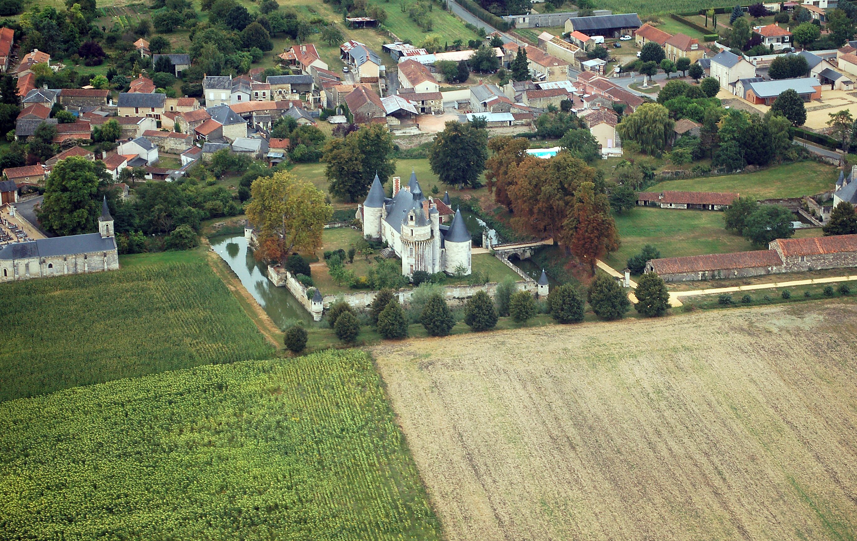 A rural village with a prominent castle, fields, and scattered houses.