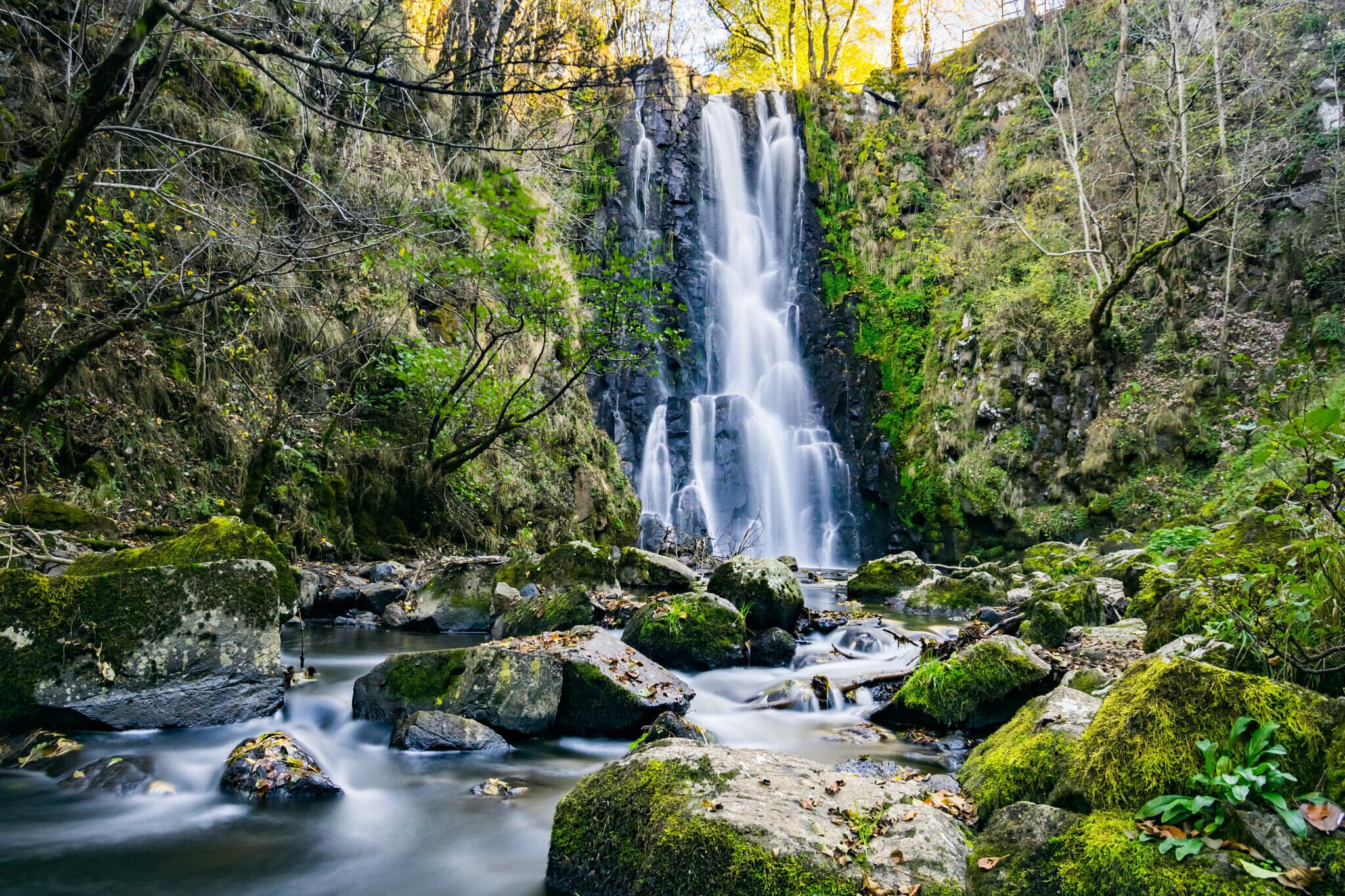 A waterfall surrounded by rocks and greenery.