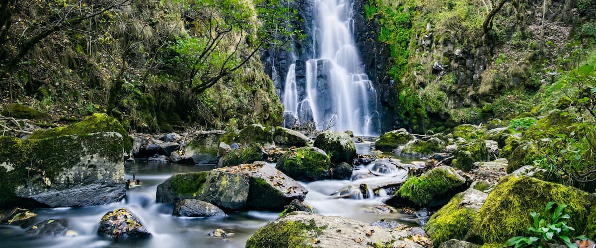 A waterfall surrounded by rocks and greenery.