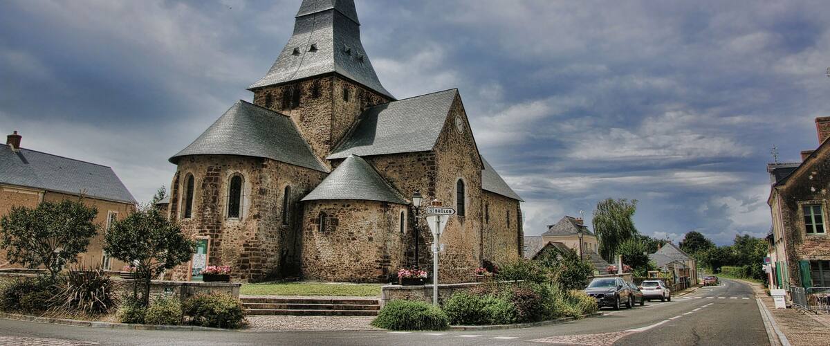A historic church with a tall spire and multiple smaller towers, surrounded by a quaint village street.