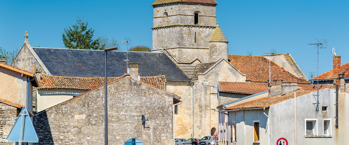 A historic town with a prominent tower, stone buildings, and a clear blue sky.