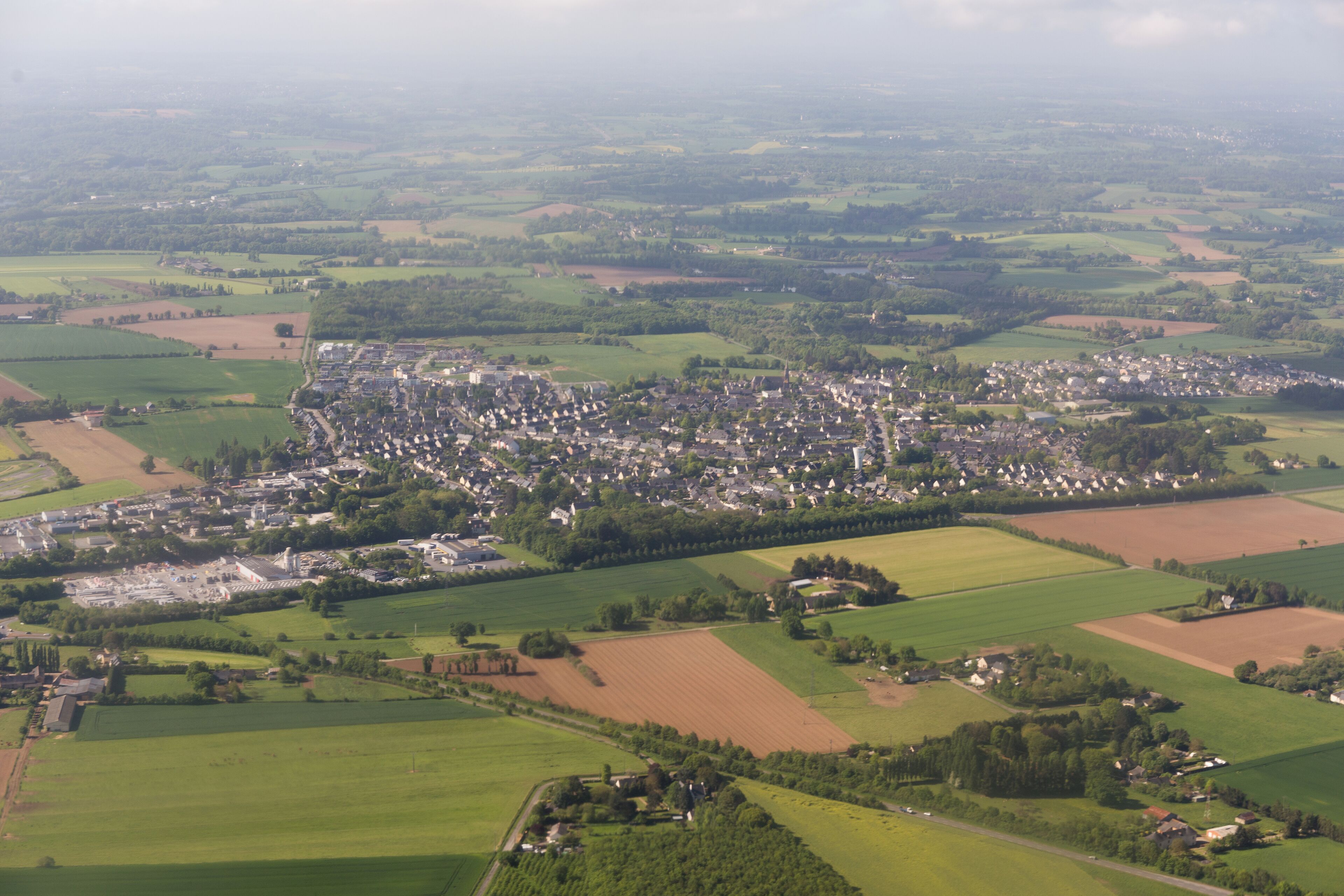 A rural landscape with a small town surrounded by fields and scattered houses.