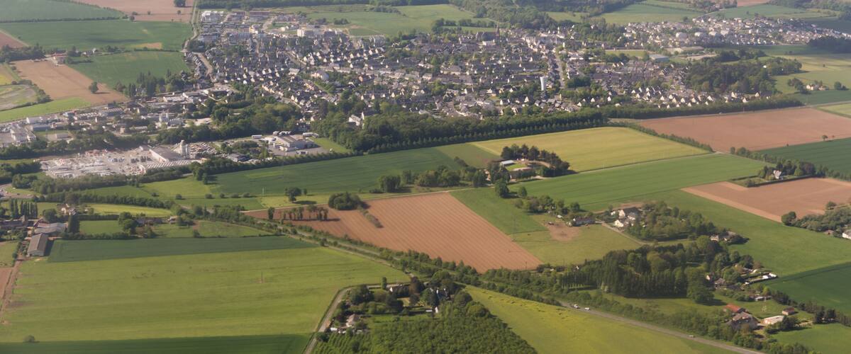 A rural landscape with a small town surrounded by fields and scattered houses.