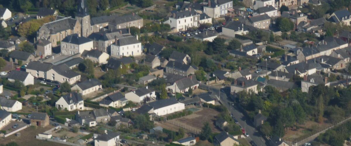 An aerial view of a densely populated residential area with houses, roads, and a church.