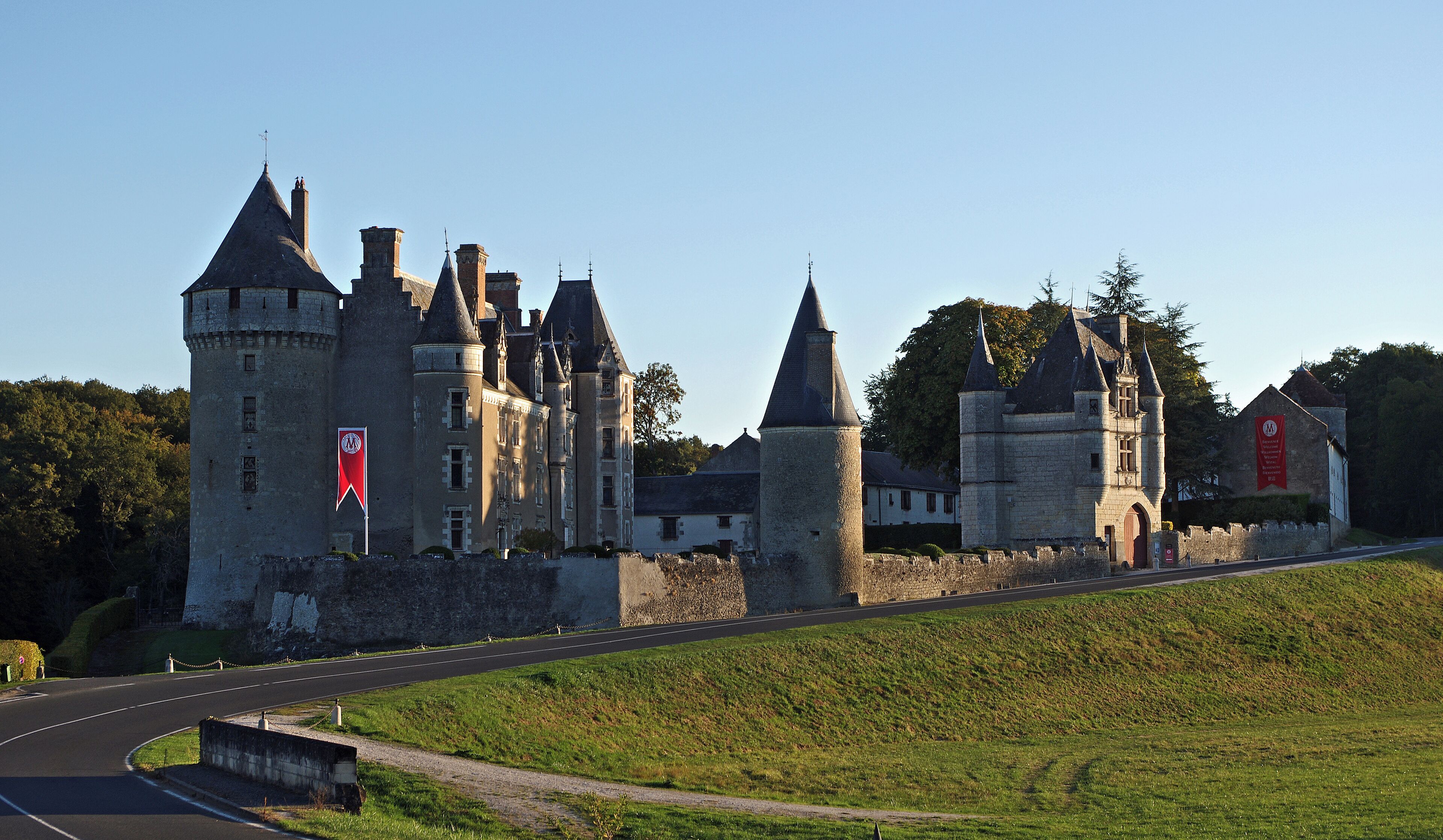 A historic castle with multiple towers and a well-maintained road in the foreground.