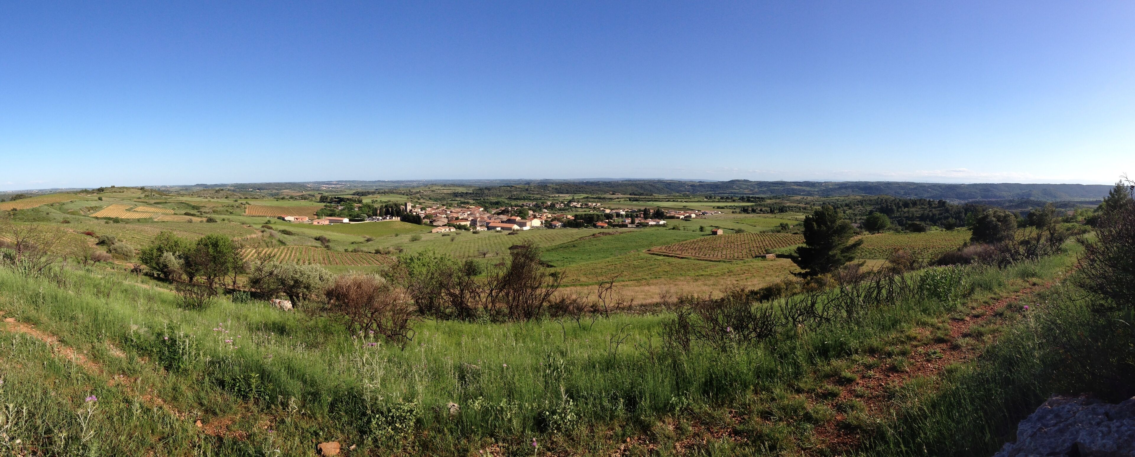A rural landscape with rolling hills, fields, and a small village.