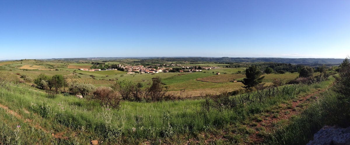 A rural landscape with rolling hills, fields, and a small village.