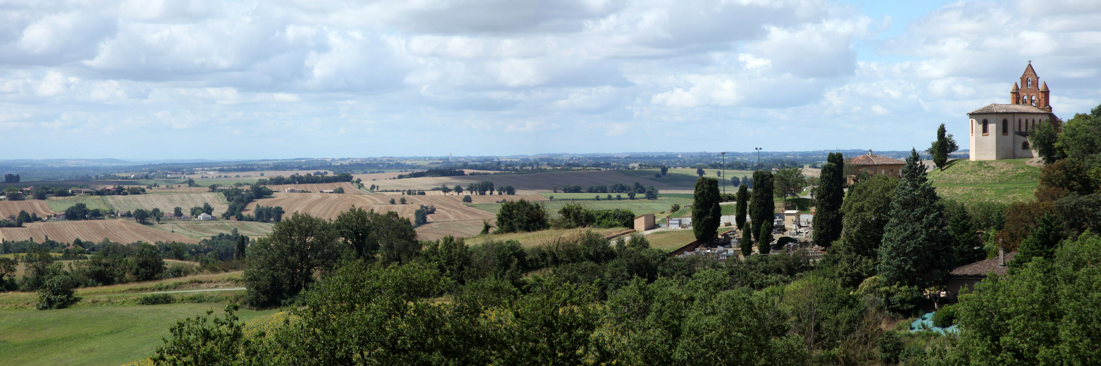 A rural landscape with rolling fields, a church, and a hilltop view.
