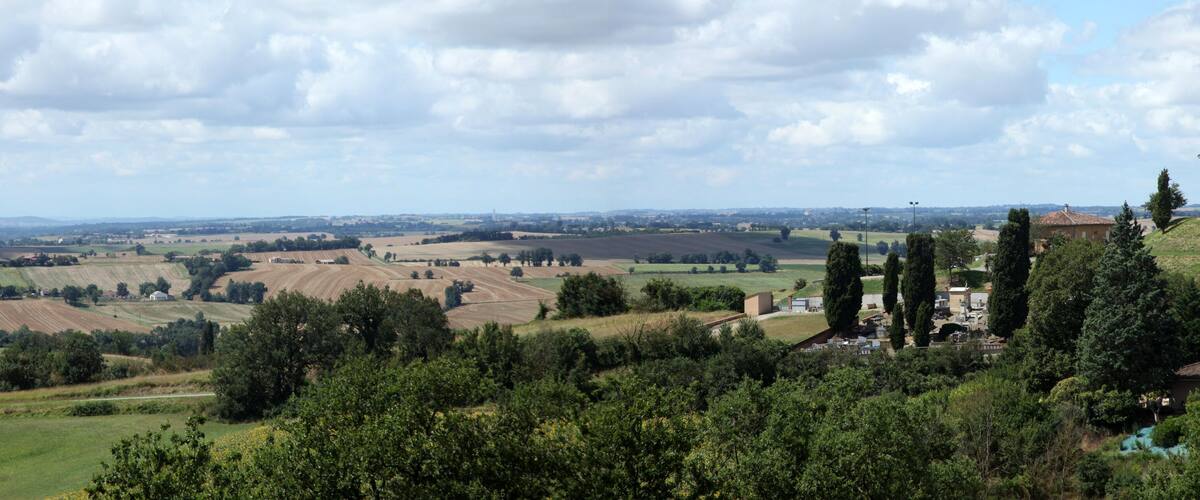 A rural landscape with rolling fields, a church, and a hilltop view.