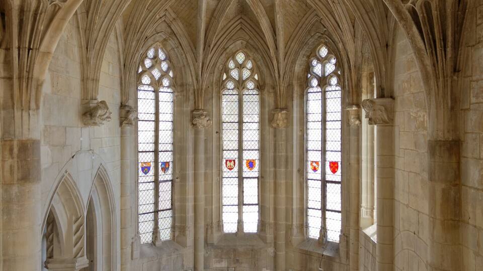 A cathedral interior with pointed arches, stained glass windows, and a central altar.