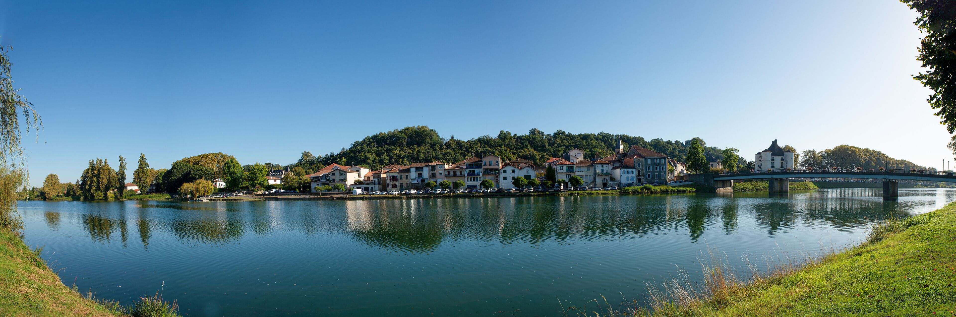 A calm lake with a bridge, buildings, and trees.