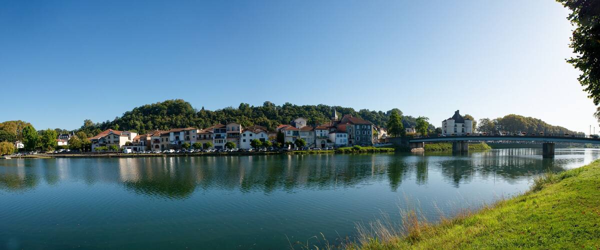 A calm lake with a bridge, buildings, and trees.