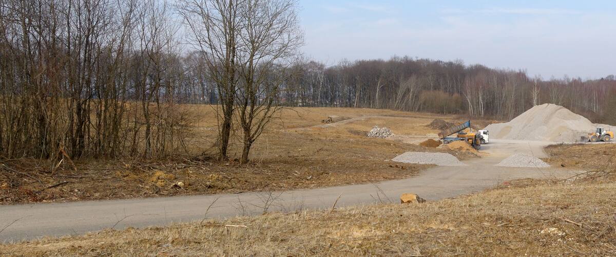 A construction site with a pile of gravel and a dirt road.