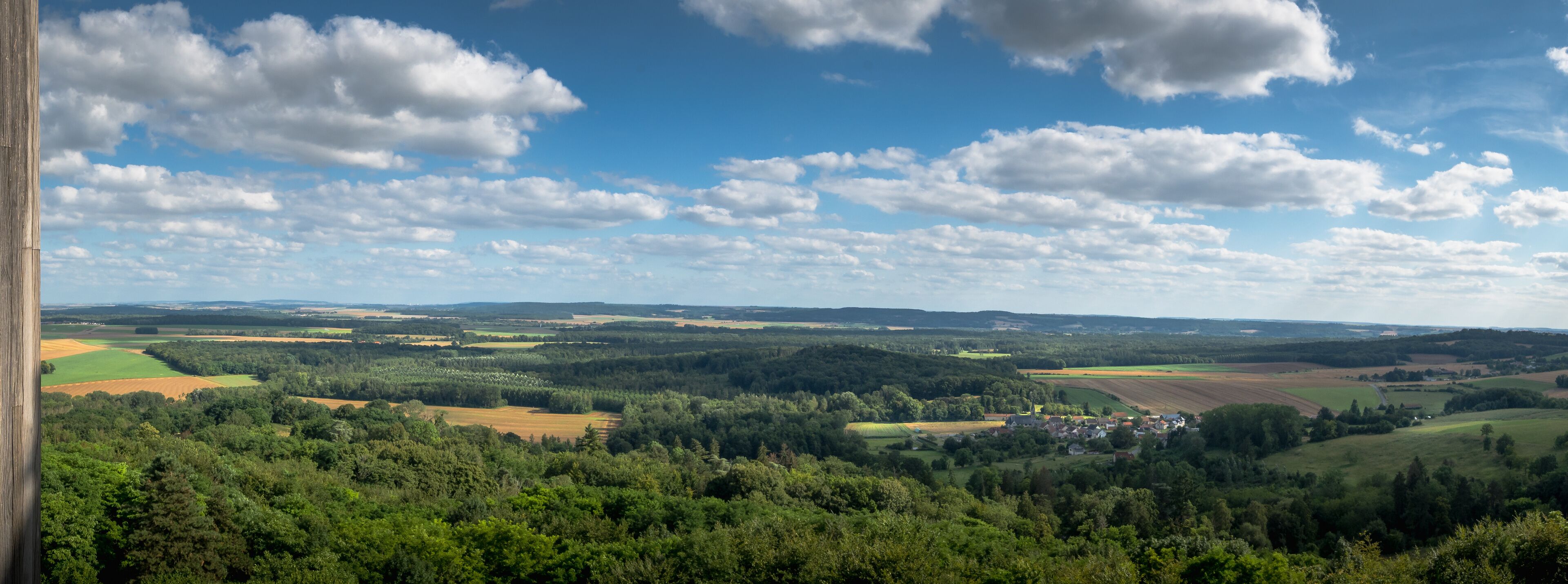 A rural landscape with rolling hills, fields, and a small village.