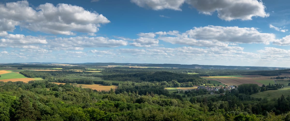 A rural landscape with rolling hills, fields, and a small village.